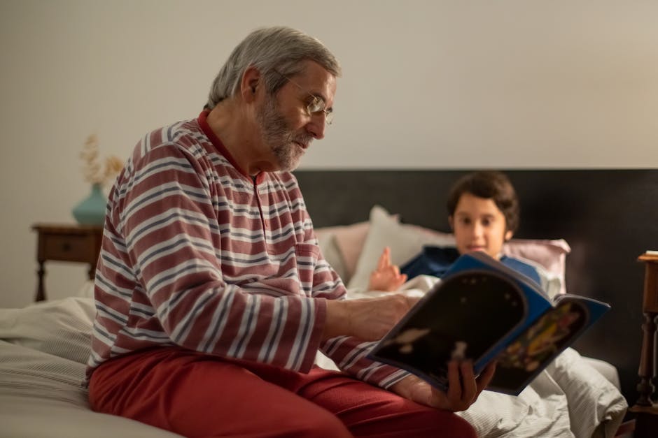 A senior man reads a bedtime story to his grandchild in a cozy indoor setting.